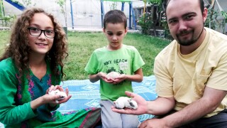 This family photo shows Ryan Corbett holding rabbits with his daughter Miriam and son Caleb in Kabul, Afghanistan in 2020.