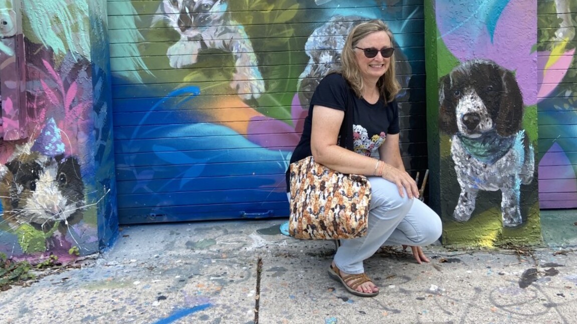 Boynton Beach resident Valerie Johnson kneels next to a painting of her dog at the _Ultimate Pet Portrait_ in Wynwood, organized by the pet supply company Chewy.jpg