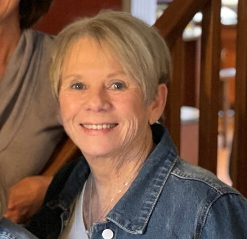 Terry West is smiling in this photo taken on Mother's Day 2021. She has blue eyes, short blonde hair and is wearing a denim jacket and white top.