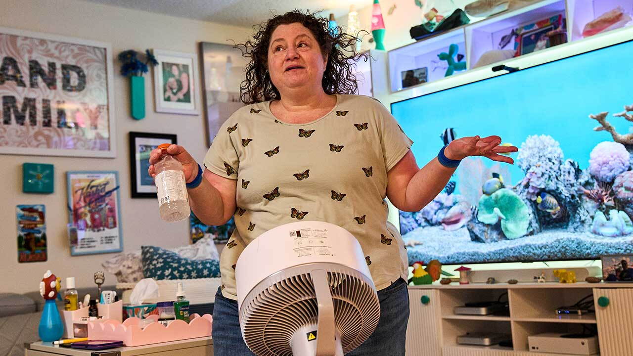 Tracy Rand uses a fan to help with her severe menopause symptoms, brought on after a surgery to remove her ovaries, at her home in Leesburg, Fla., Friday, Aug. 14, 2026. (AP Photo/Jacquelyn Martin)