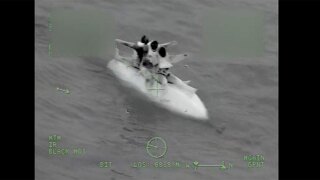 Three boaters wave from the hull of a capsized boat off Captiva Island, Fla. on Feb. 23, 2025.