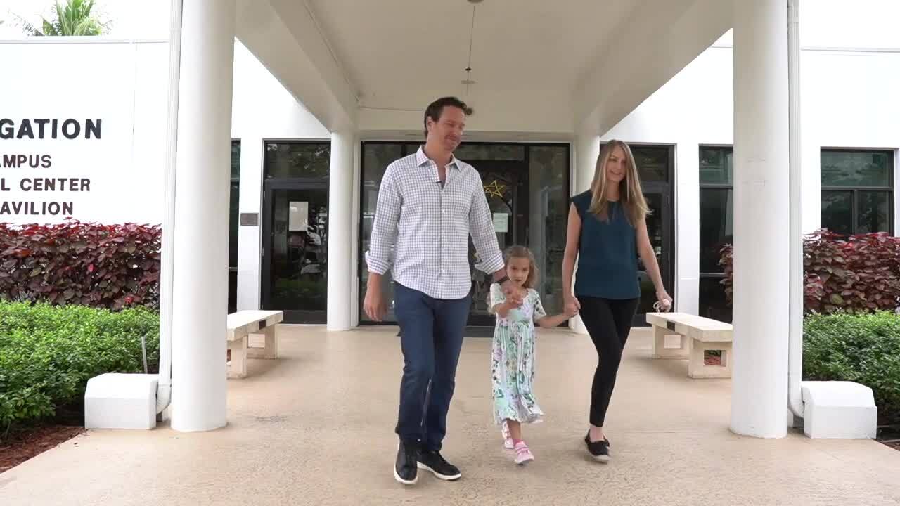 Stephanie and Eric Hochberger hold hands with daughter as they leave B'Nai Jewish Congregation