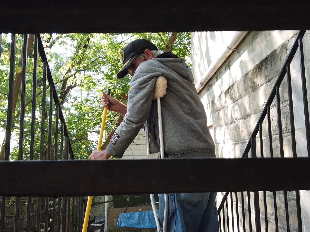 Terry Walls sweeping the back steps of the Joe Williams Family Center. The photo was taken from behind the staircase and shows Walls pictured between several steps.
