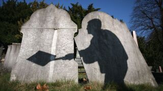 Shadow of a cemetery worker cast on gravestones.