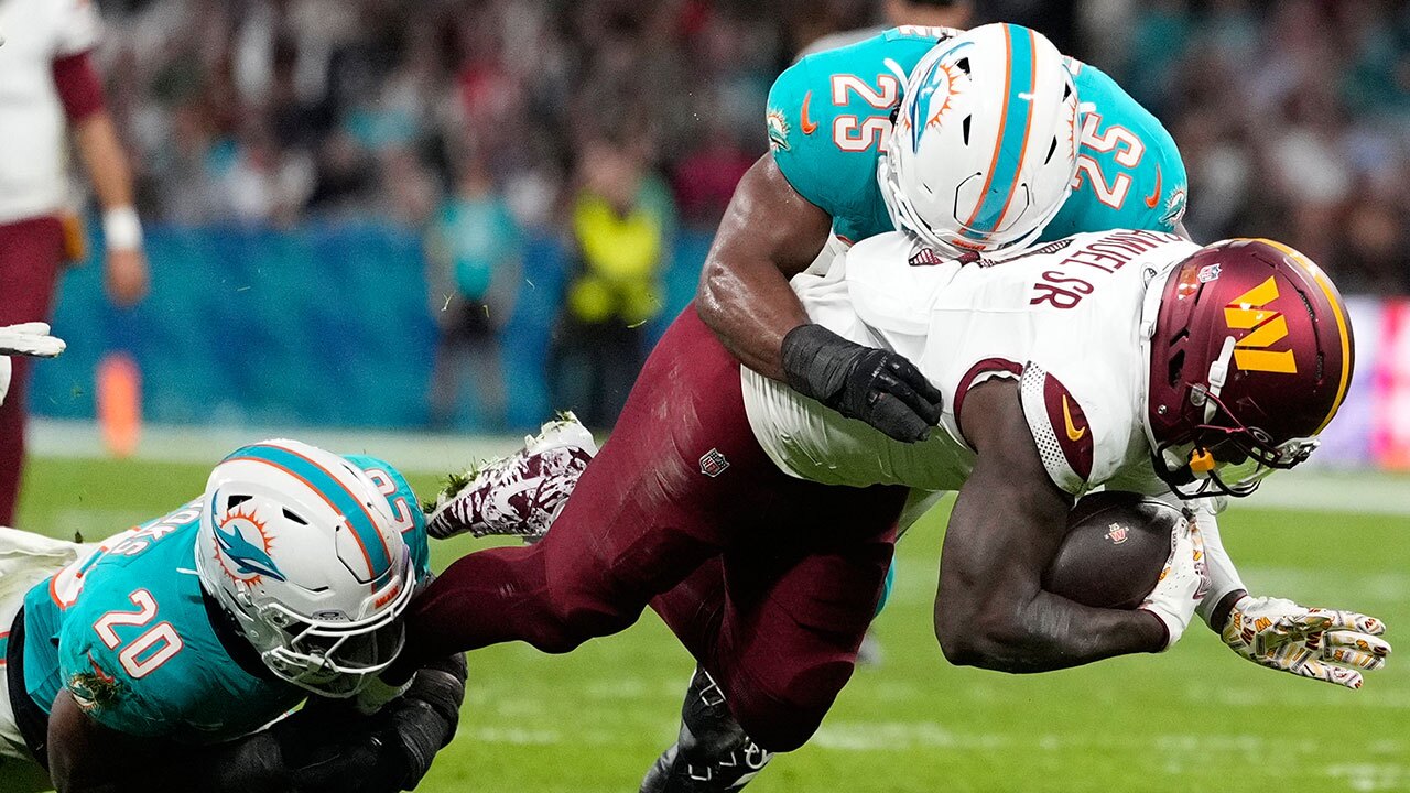 Washington Commanders wide receiver Deebo Samuel (1) is tackled by Miami Dolphins linebacker Jordyn Brooks (20) and linebacker Tyrel Dodson (25) during the first half of an NFL football game between the Washington Commanders and the Miami Dolphins in Madrid, Spain, Sunday, Nov. 16, 2025. (AP Photo/Bernat Armangue)