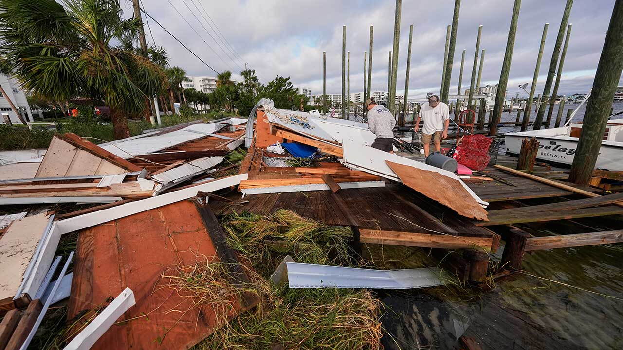People retrieve belongings from a collapsed boat house in the aftermath of Hurricane Isaias in Destin, Fla., Saturday, Oct. 10, 2026. (AP Photo/Gerald Herbert)