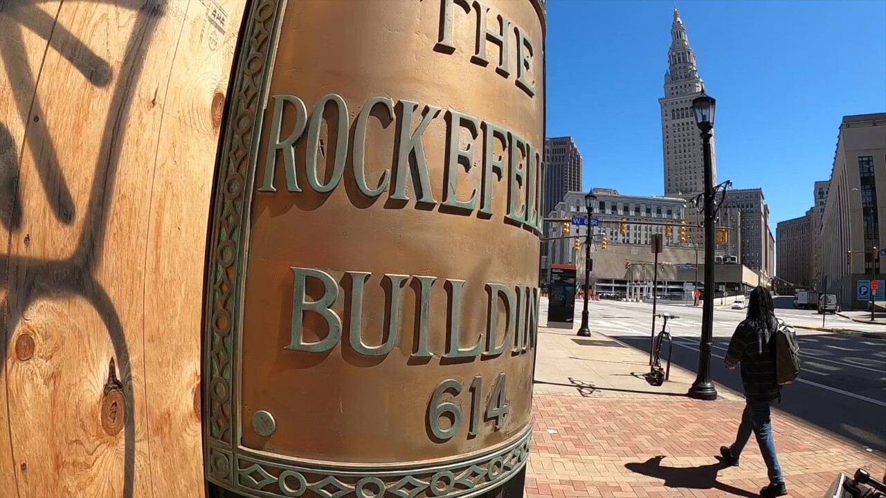 A pedestrian passes the boarded-up Rockefeller Building in downtown Cleveland.