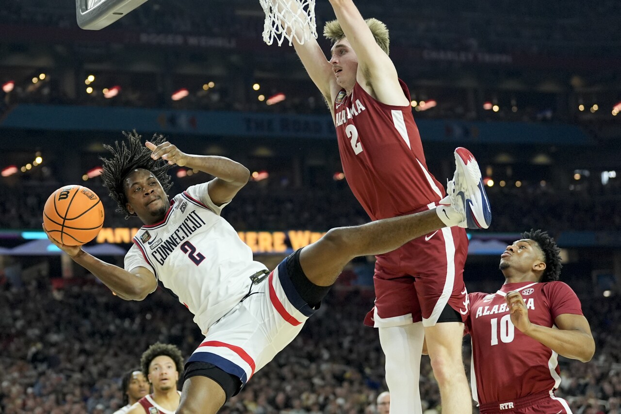 UConn Huskies guard Tristen Newton passes around Alabama Crimson Tide forward Grant Nelson in second half of Final Four, April 6, 2024