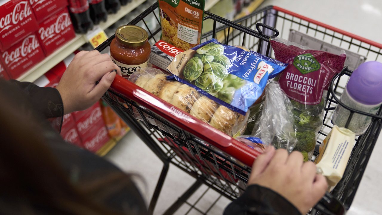 A food shopper pushes a cart of groceries at a supermarket