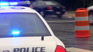 Close up of a police car with traffic driving by from Videoblocks.