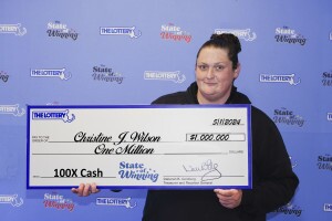 A woman holds up a large check with her lottery winnings