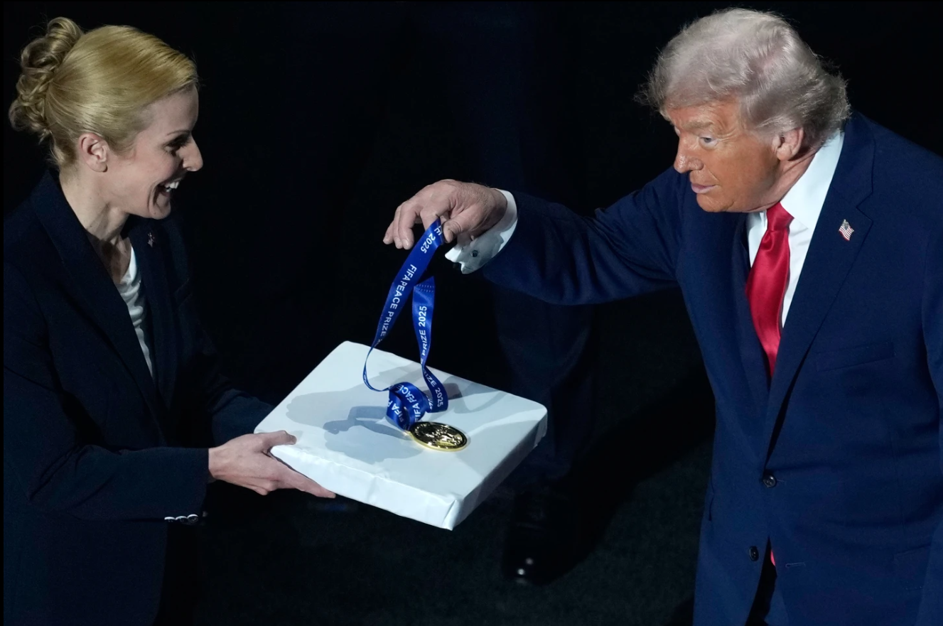 President Donald Trump picks up his FIFA Peace Prize medal, awarded to him by FIFA President Gianni Infantino, before the draw for the 2026 soccer World Cup at the Kennedy Center in Washington, Friday, Dec. 5, 2025.