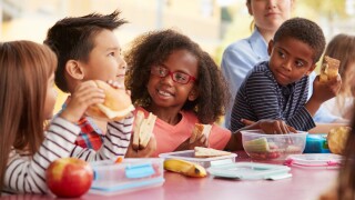 Young,School,Kids,Eating,Lunch,Talking,At,A,Table,Together