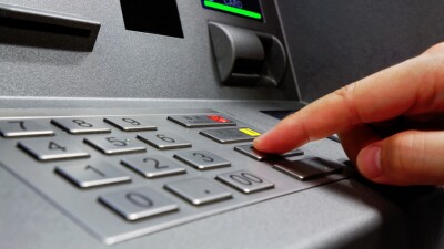 A person presses buttons on an ATM.