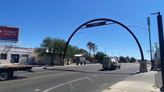 Regular car traffic passes under arch marking Cesar Chavez Avenue at Five Points intersection