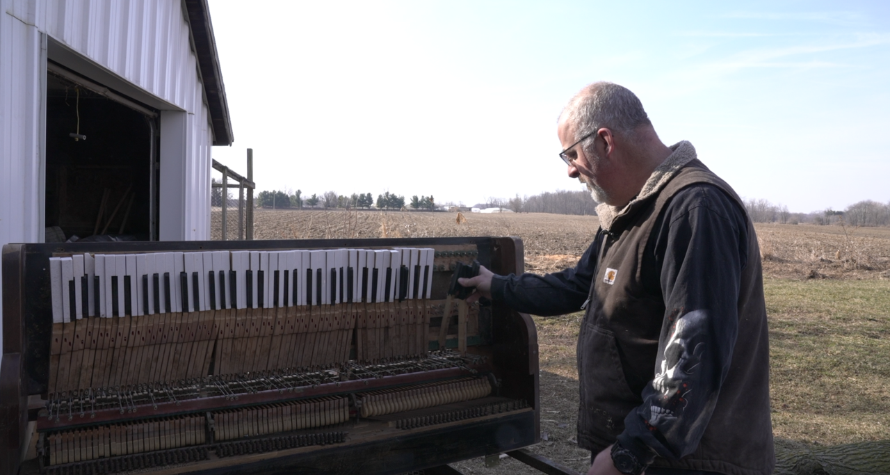 Jon Boza next to a piano he is repurposing