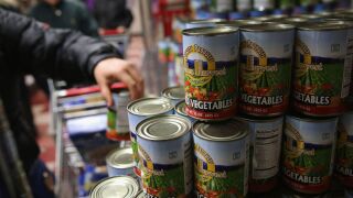 A man picks up a can of vegetables offered through the SNAP program.