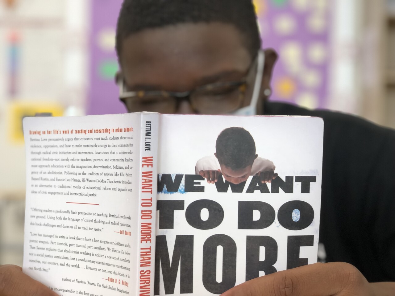 An Aiken High School student reads in preparation for a discussion with Keith Lamar, a death row inmate at the Ohio State Penitentiary. The student is wearing glasses and a mask and is reading "We Want to Do More Than Survive" by Bettina Love.