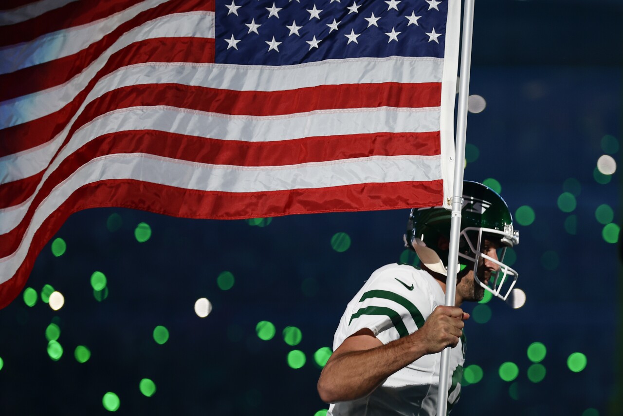 New York Jets QB Aaron Rodgers runs onto field carrying American flag, Sept. 11, 2023