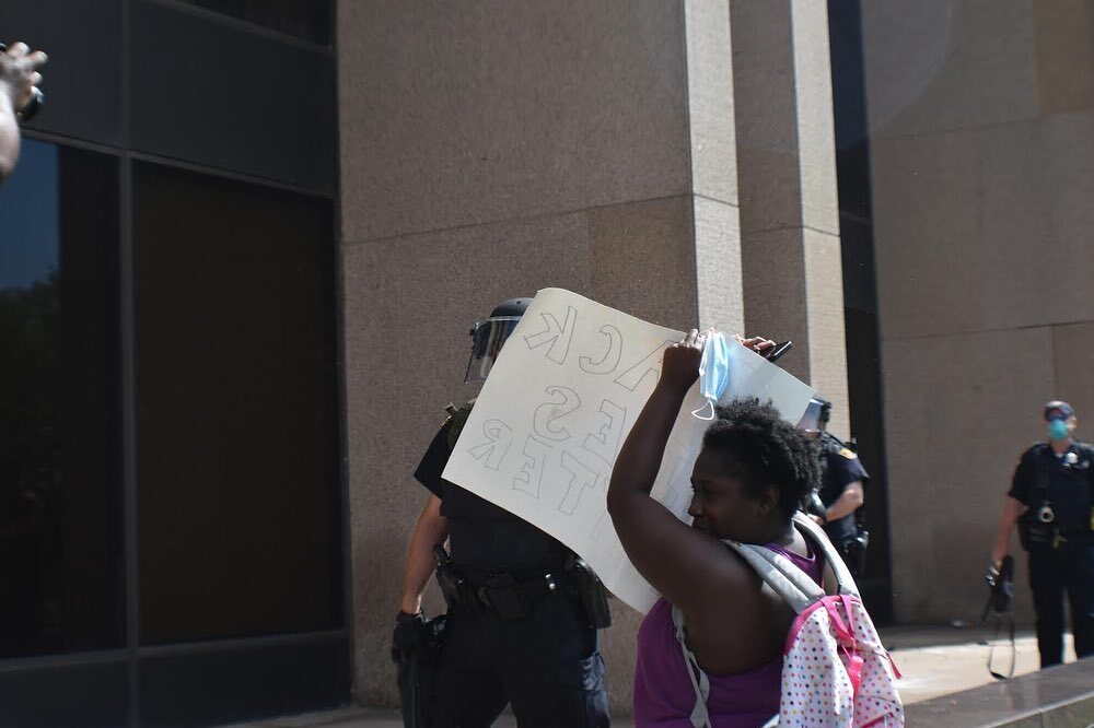 Woman holds sign over face