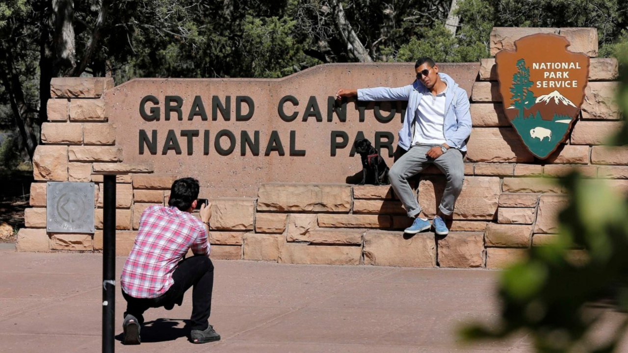 Visitors taking photos at the Grand Canyon National Park entrance.