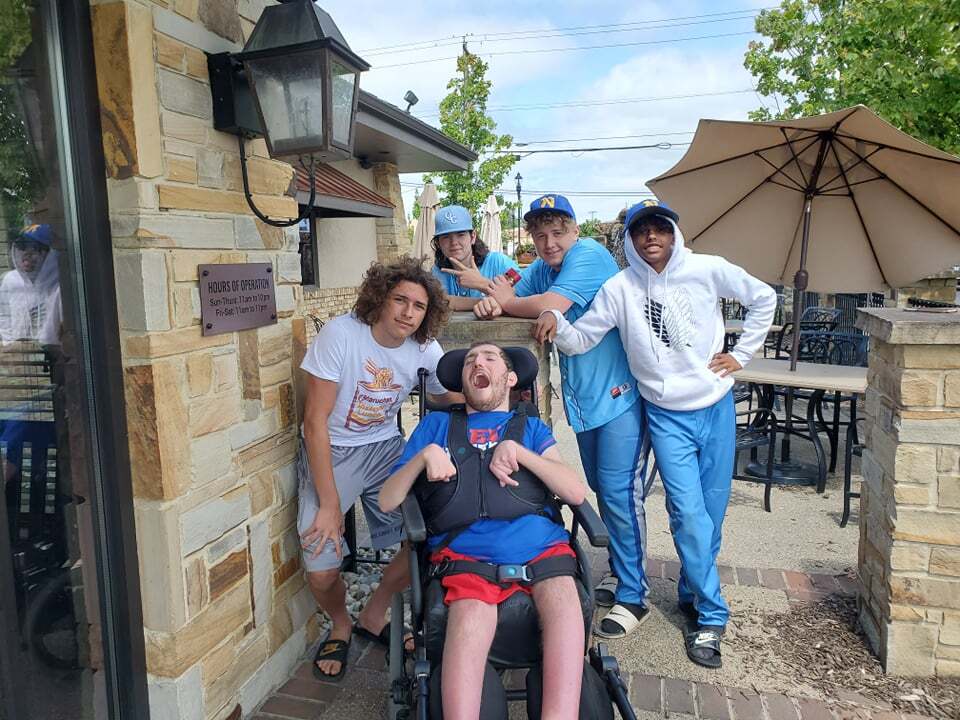 This photo shows Ethan Kadish in his wheelchair posing with friends after attending a baseball tournament in July 2021.