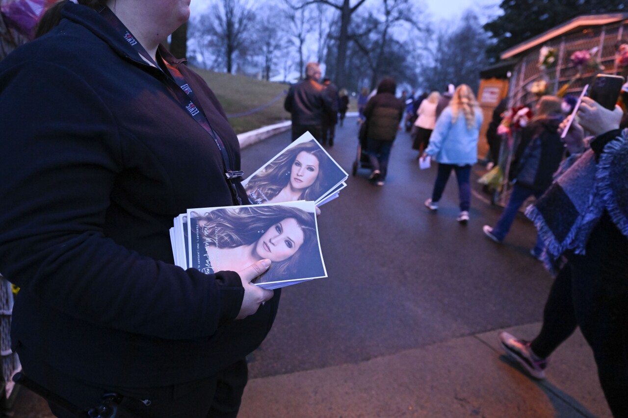 Attendant holds programs as fans enter Graceland for Lisa Marie Presley's memorial, Jan. 22, 2023