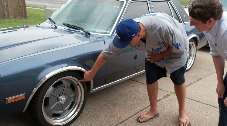 Milton Peko showing a dent in his rim from a pothole on his street