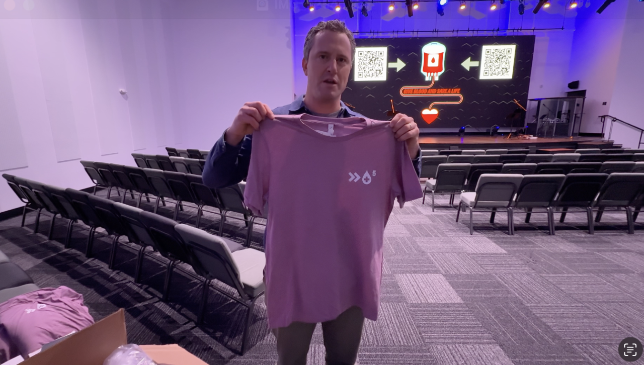 Andy Levy holds up new blood drive t-shirt