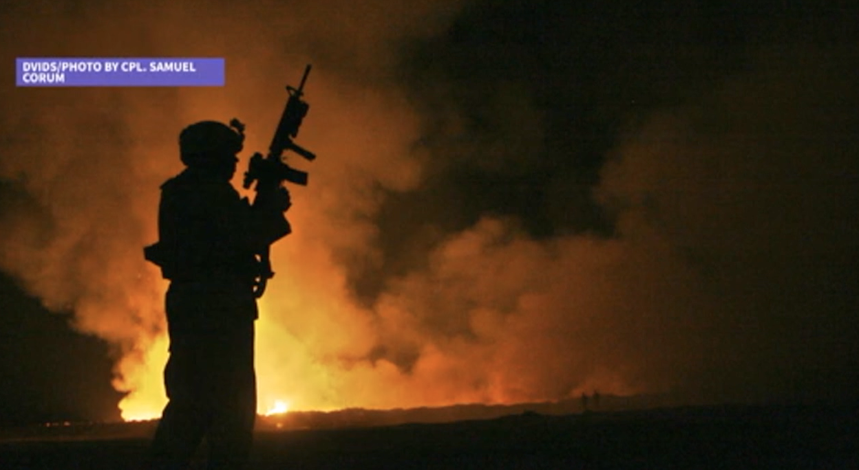 Soldier stands near burn pit in the Middle East