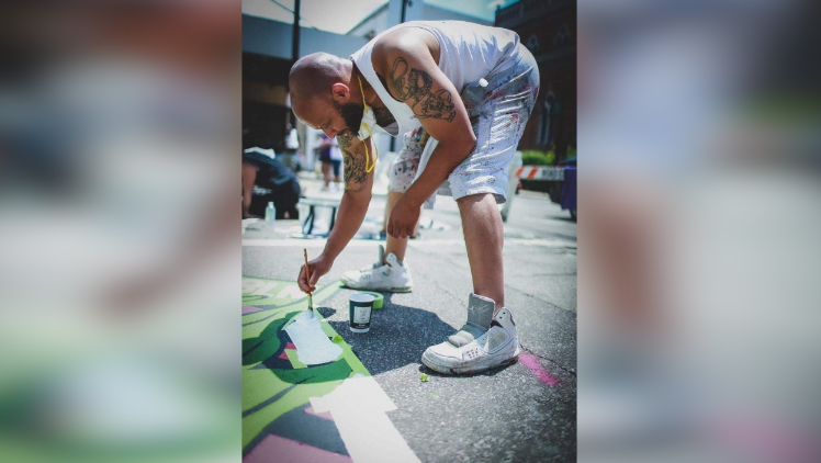 Brandon Hawkins painting the B in the Black Lives Matter mural