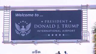 Workers at the airport entrance on July 8, 2026, installed a new sign that says "Welcome to President Donald J. Trump International Airport."