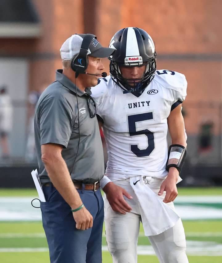 Craig Tibbe talks to a player on the sideline of a game