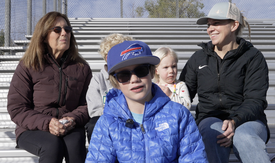 Following tradition, Alex Vaughn, finds a spot in the bleachers with donuts, to support as his dad, Tim, crosses the finish line.