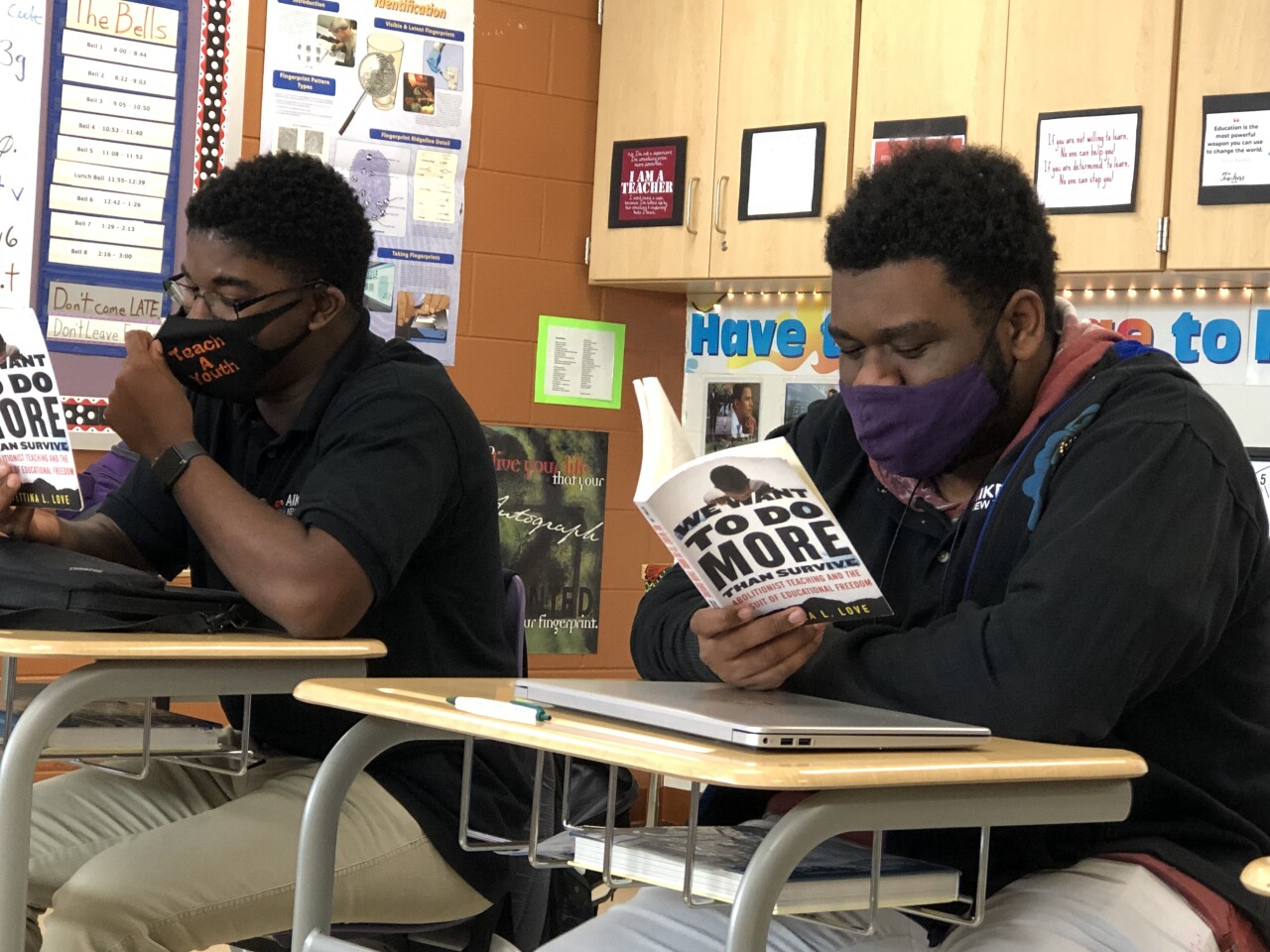 Two Aiken High School students read in preparation for their book club with Keith LaMar. Both students have short, dark hair and are wearing masks.