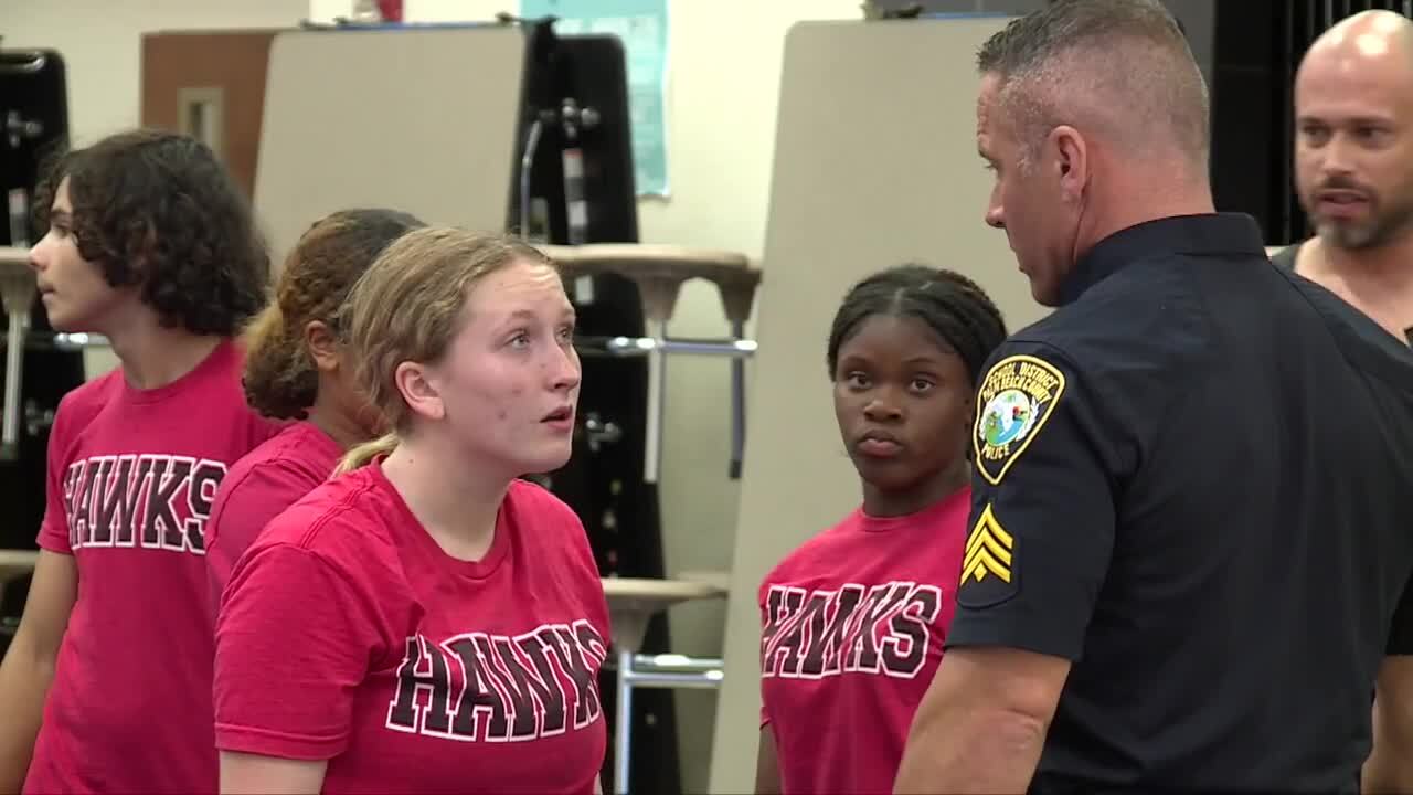 Sgt. Philip Salm speaks to his daughter, Madelyn Salm, during cheerleading practice at Seminole Ridge Community High School on Sept. 7, 2023.jpg