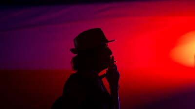 A silhouetted man smokes a cigarette