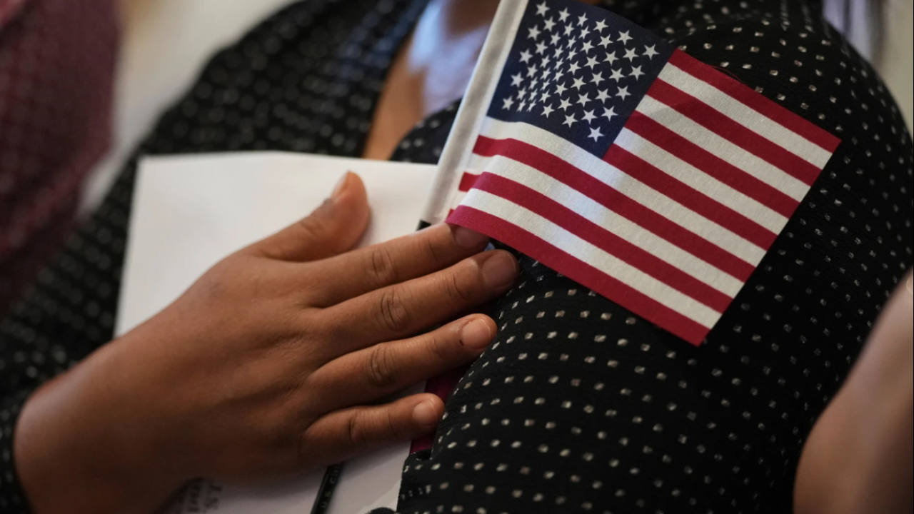 A woman clutches a U.S. flag as she and applicants from other countries prepare to take the oath of citizenship in commemoration of Independence Day during a Naturalization Ceremony in San Antonio, Texas, July 3, 2025.