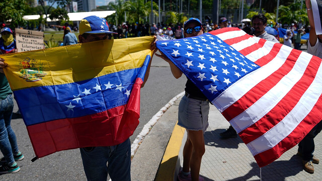 Demonstrators hold a Venezuelan and U.S. national flags during a student-led march calling for the release of people considered political prisoners on National Youth Day, in Caracas, Venezuela, Thursday, Feb. 12, 2026. 