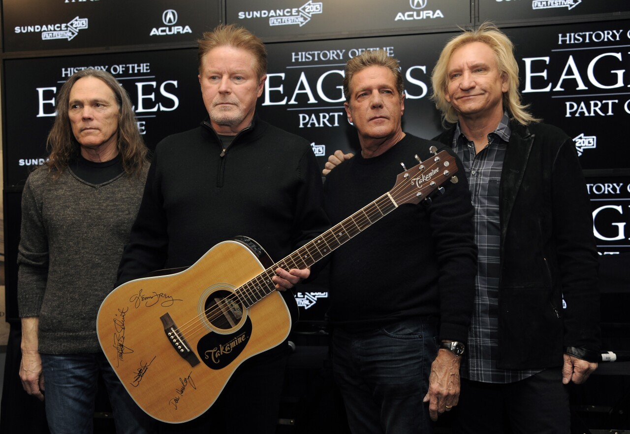 FILE - Members of The Eagles, from left, Timothy B. Schmit, Don Henley, Glenn Frey and Joe Walsh pose with an autographed guitar after a news conference at the Sundance Film Festival, in Park City, Utah, Jan. 19, 2013. Three people were charged Tuesday, July 12, 2022, in an alleged conspiracy involving the handwritten lyrics to the classic rock juggernaut "Hotel California." (Photo by Chris Pizzello/Invision/AP, File)