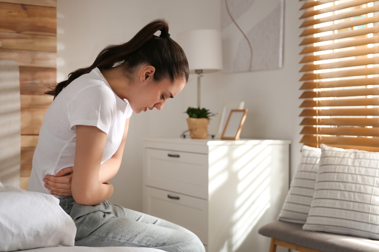 Young,Woman,Suffering,From,Stomach,Ache,On,Bed,At,Home,