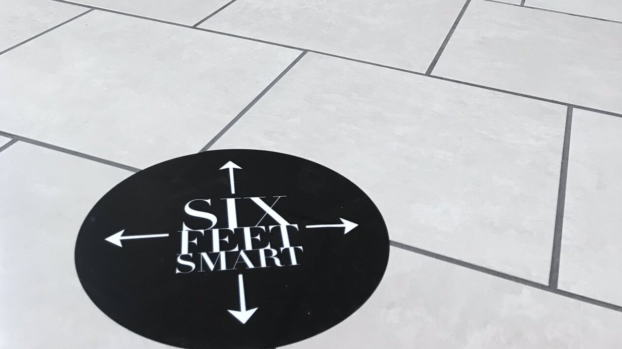 A sign on the floor at the Gardens Mall emphasizes customers to stay 6 feet apart.