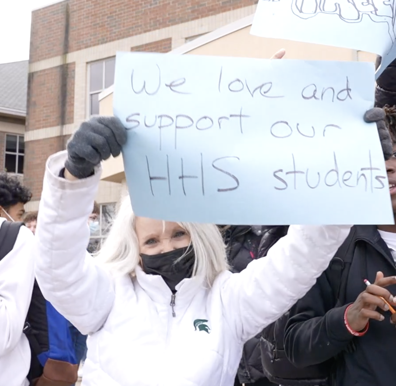 Holt teacher stood next to students holding a sign of support.
