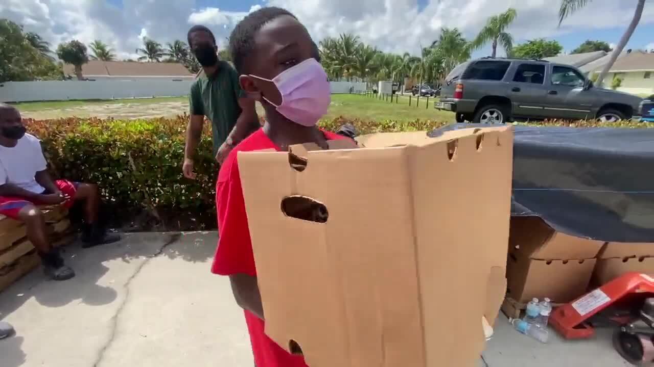 Boy hands out box of food in Lake Worth Beach to those in need