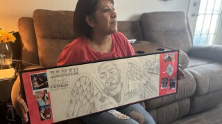 Letty Perez hold a drawing of her son Roman Perez with wings.