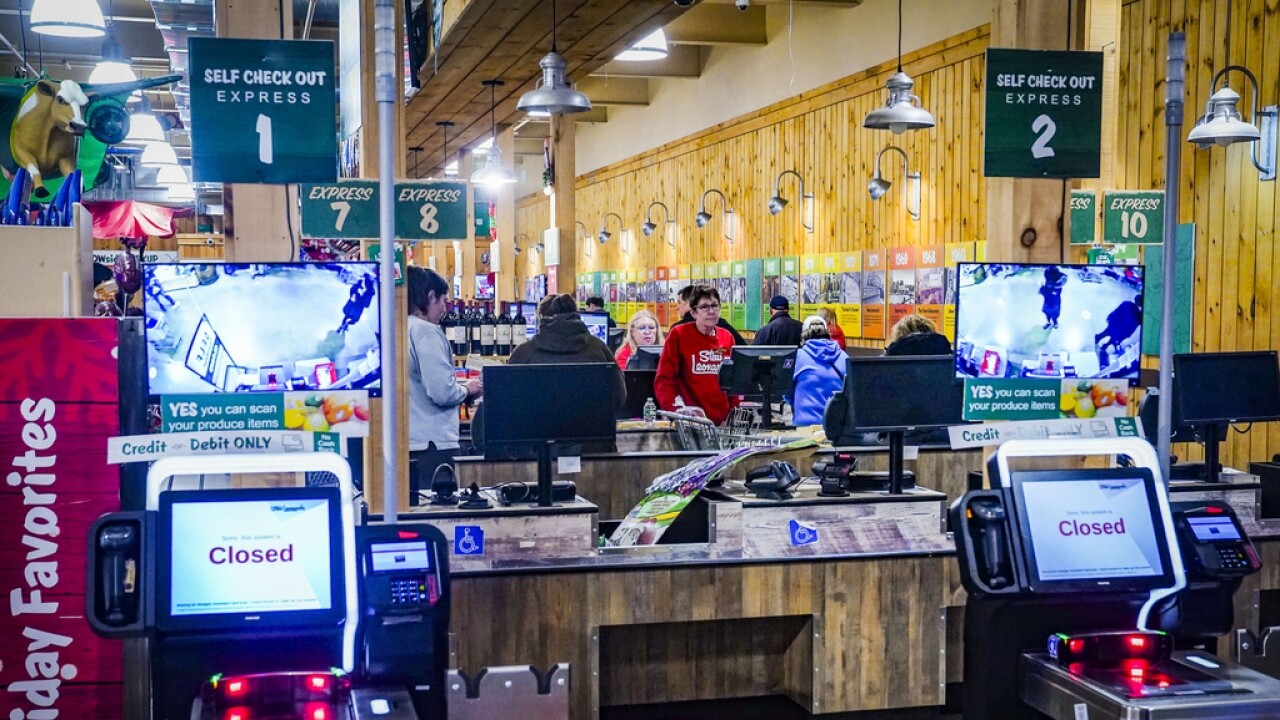 Customers checkout at registers with cashiers near a section of self-checkout kiosks at Stew Leonard's grocery store.