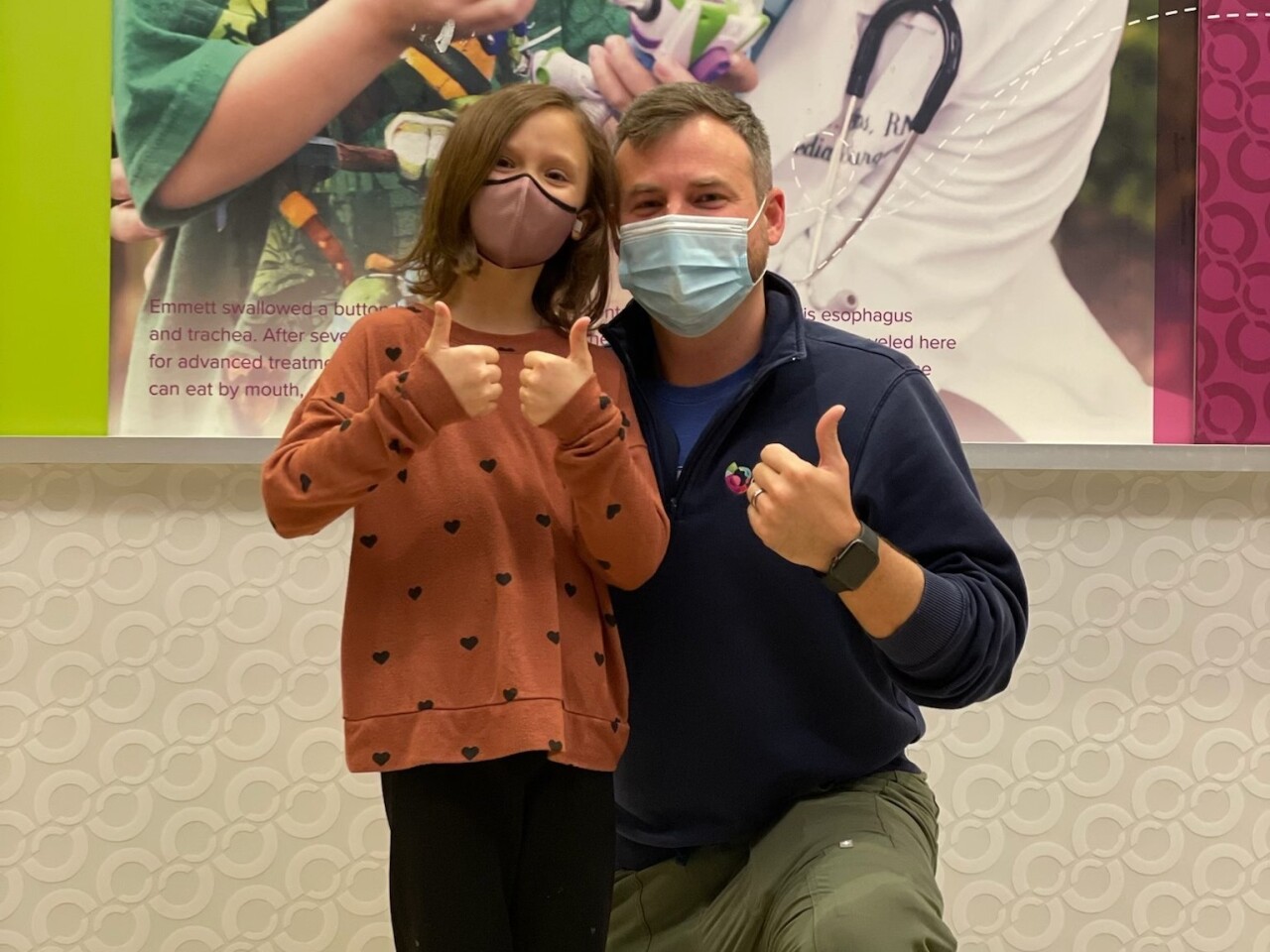 Ellory McClure, left, with one of her favorite nurses at Cincinnati Children's Hospital Medical Center after a recent medical love drop. Both are wearing masks and giving a thumbs up.