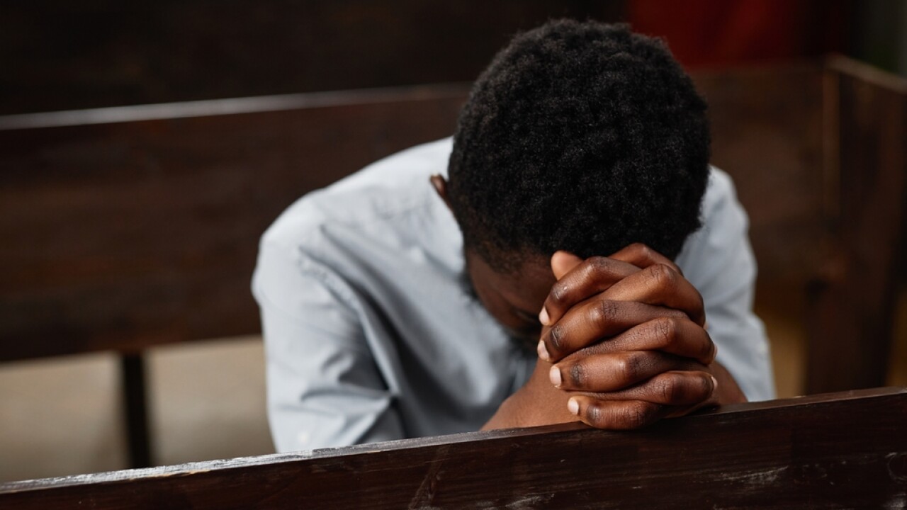 Young,African,American,Man,Sitting,On,Bench,And,Praying,In