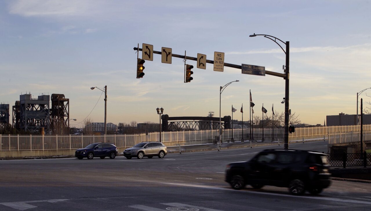 A video shows cars driving through an intersection under changing stop lights. A surveillance camera is mounted on the stoplight pole.