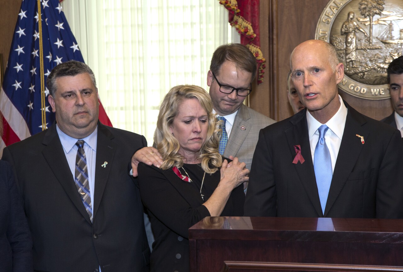 Tony Montalto, Gena Hoyer and Ryan Petty stand next to Gov. Rick Scott before he signs Marjory Stoneman Douglas Public Safety Act, March 9, 2018